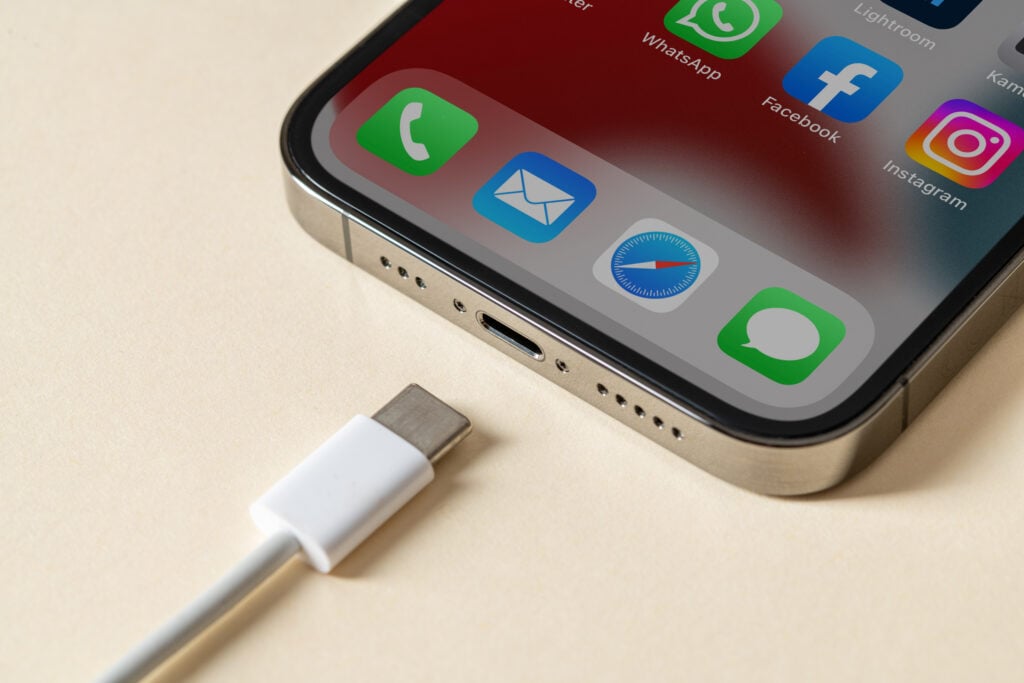 An iPhone lying next to a USB-C cable, ready to be plugged in.