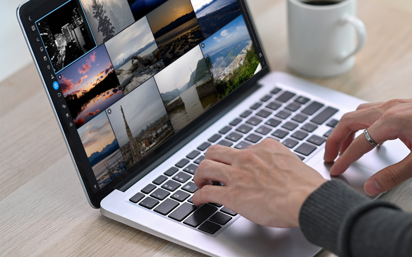 Hands typing on a laptop keyboard while Mylio Photos shows a grid of landscape photos on screen.